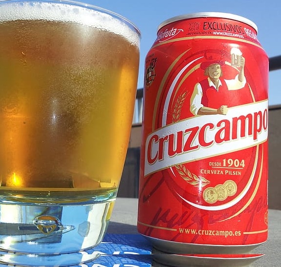 Lata y vaso lleno de Cerveza Cruzcampo Pilsen
