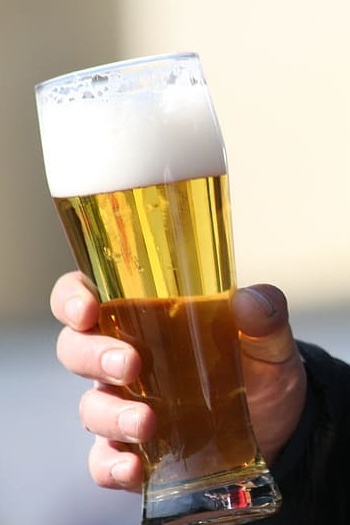 Una mano sosteniendo un vaso lleno de Cerveza Pilsen